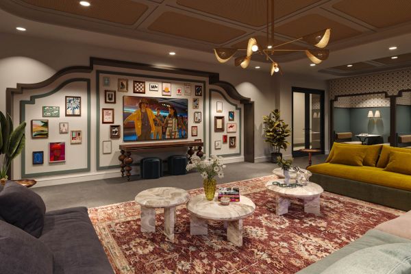 Clubroom at VERVE Columbia featuring eclectic wall art, sculptural lighting, marble coffee tables, and a patterned red rug in a warm, inviting lounge setting.