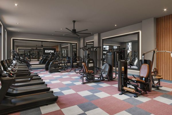 Fitness center at VERVE Columbia showcasing a range of cardio and strength equipment, wall-mounted TVs, ceiling fans, and a colorful checkered floor design.