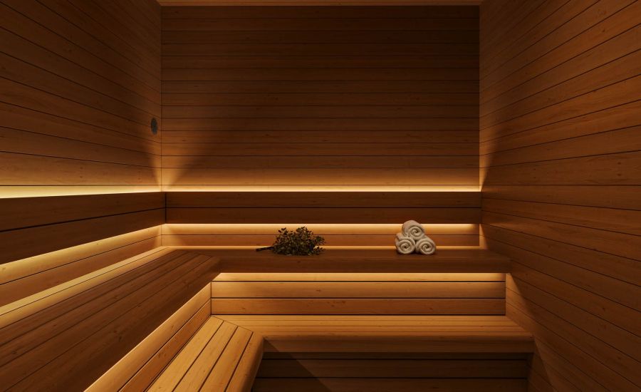 Wood-paneled sauna at VERVE Columbia featuring warm ambient lighting, tiered bench seating, and rolled towels—designed for relaxation and post-workout recovery.