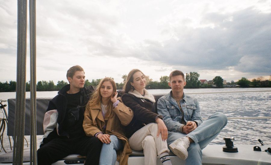 Group of four college friends sitting on a boat in jackets