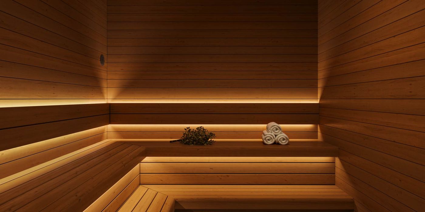 Wood-paneled sauna at VERVE Columbia featuring warm ambient lighting, tiered bench seating, and rolled towels—designed for relaxation and post-workout recovery.