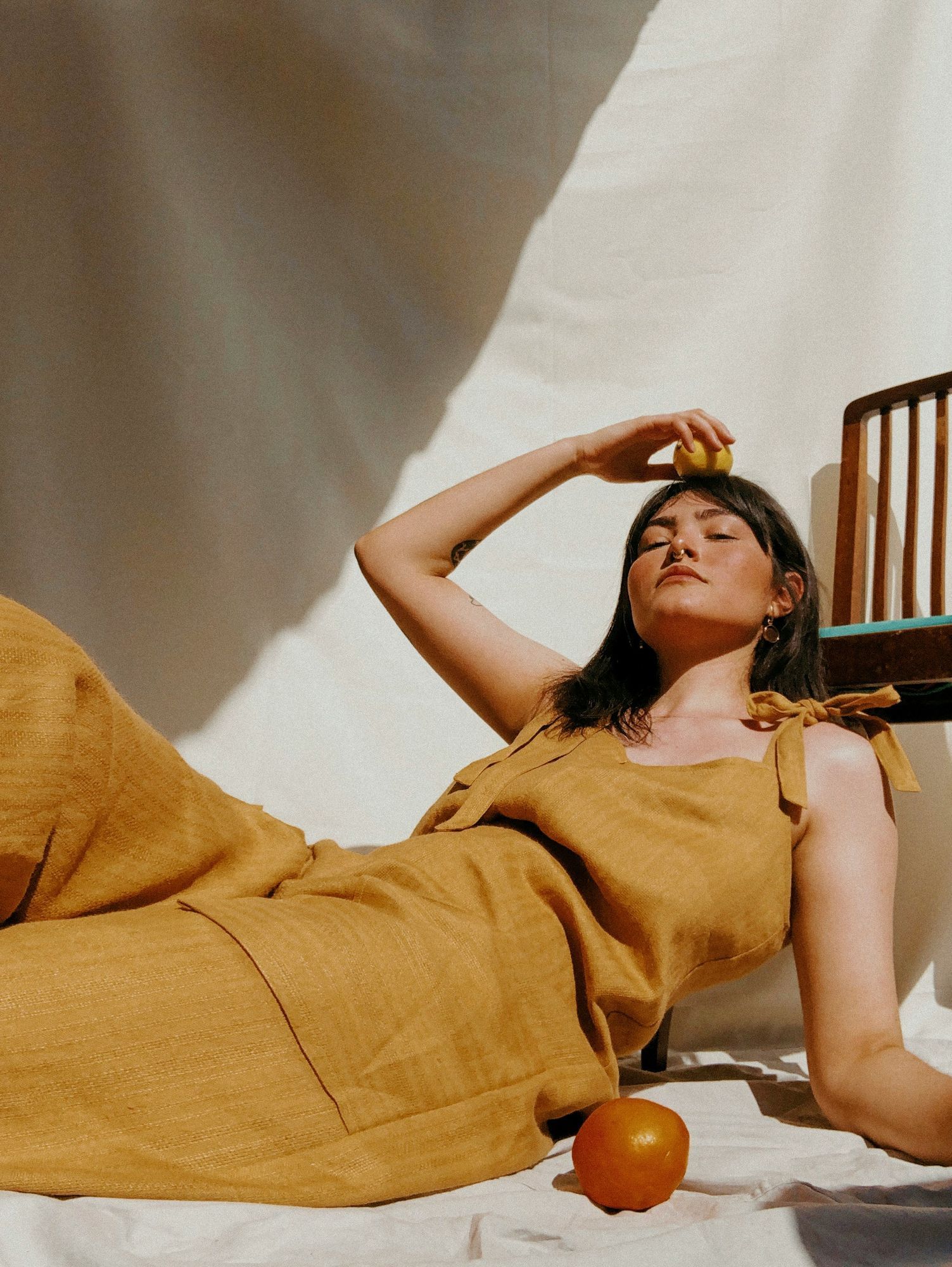 Woman in a mustard-colored outfit reclining against a neutral backdrop with sunlight casting soft shadows, captured at VERVE Columbia.