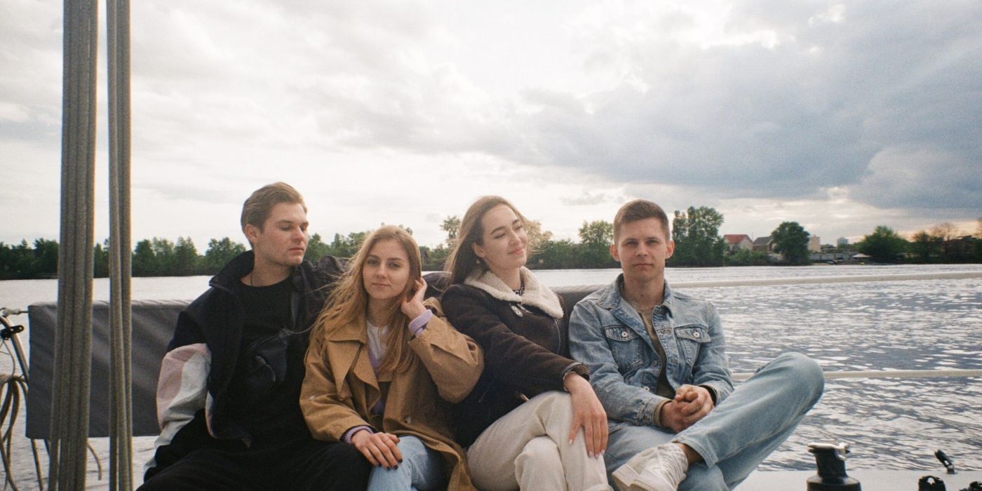 Group of four college friends sitting on a boat in jackets